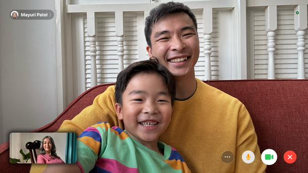 Two people smiling at camera during a video call, wearing yellow and colorful striped shirts.