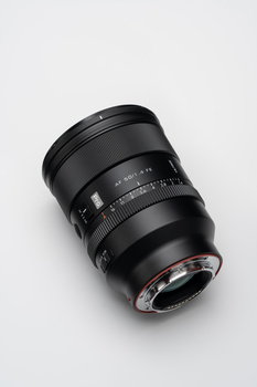 Black telephoto lens with focus ring and distance scale markings against a light background.