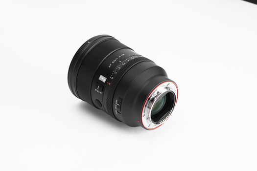 Black telephoto lens with red AF/MF switch ring and distance scale markings on white background.