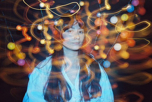 Portrait with light trails and bokeh creating abstract, colorful patterns around a figure's head.