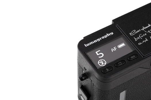 Close-up of camera flash display showing AF mode and flash settings on textured camera body.