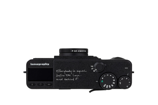Top-down view of a black mirrorless camera with handwritten text on its body and a prime lens mounted.
