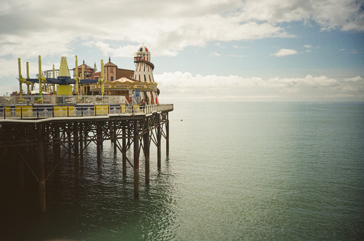 Ornate pier structure with Victorian architecture extending into calm turquoise waters under partly cloudy sky.