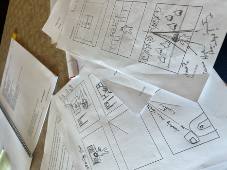 Scattered storyboard sketches and wireframes on a wooden desk with notes and annotations.