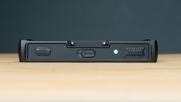 Top view of a black spirit level tool with bubble indicators and mounting hardware on a wooden surface.
