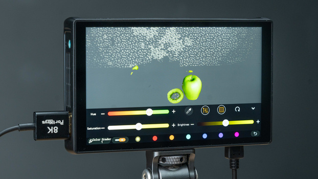 Monitor displaying color grading interface with green apples and particle effects in preview window.