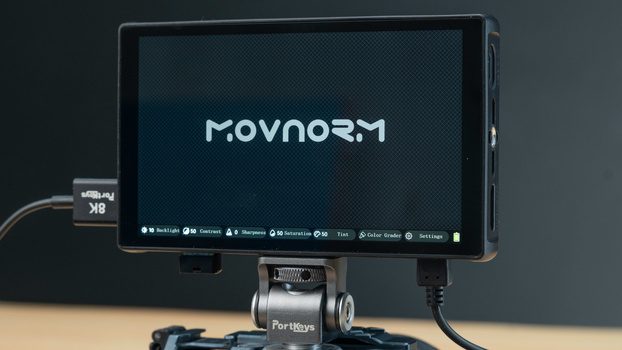Movnorm monitor mounted on a camera rig with external controls and cables connected.