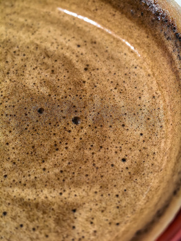 Close-up of a textured ceramic or pottery surface with a speckled tan glaze and dark spots.