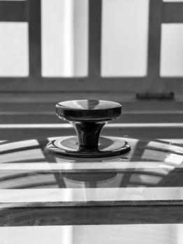 Chrome hood ornament mounted on a car roof against an urban building backdrop.