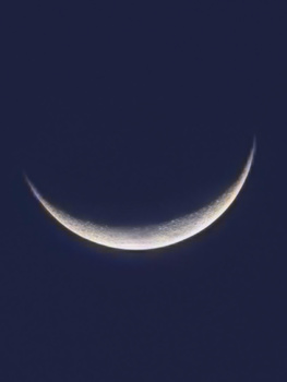 Crescent moon against dark night sky with soft golden illumination along curved edge.