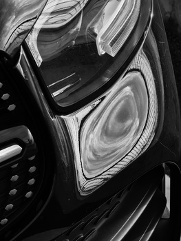 Close-up black and white photograph of a motorcycle headlight and fairing detail.