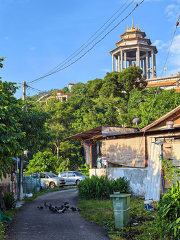 Narrow alleyway with weathered buildings leading to a golden-domed structure on a hilltop.