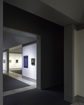 Modern gallery entrance with deep black frame and white interior walls displaying framed artwork.