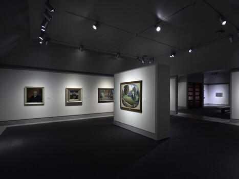 Modern gallery interior with framed photographs displayed on white walls under track lighting.