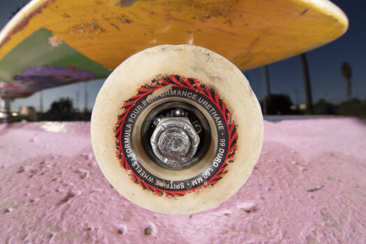 Close-up view of a skateboard wheel and grip tape shot from directly above the deck.