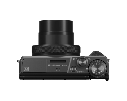 Top-down view of a compact mirrorless camera with attached lens and visible control dials.