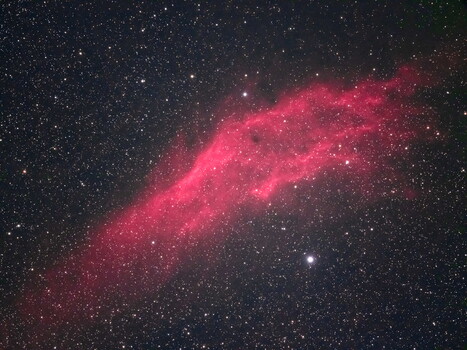 Pink emission nebula streaking diagonally across a starfield.
