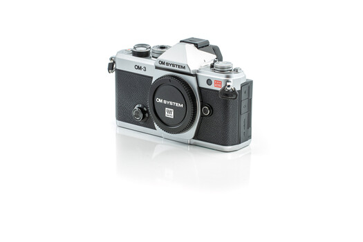 OM System OM-3 35mm SLR camera body with chrome and black finish against white background.
