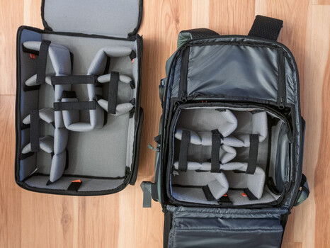 Two open camera equipment cases displaying drone components and foam dividers on a wooden floor.
