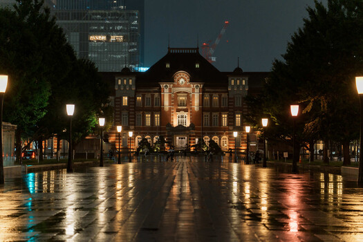 Historic brick building with illuminated facade reflected on wet plaza at night.