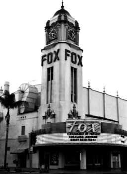 Black and white photograph of a historic theater tower with art deco architecture and marquee signage.