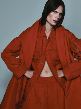 Person wearing oversized rust-colored button-up shirt and matching pants against neutral background.