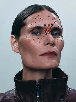 Portrait of a person with distinctive red freckle-like markings across their face and forehead.