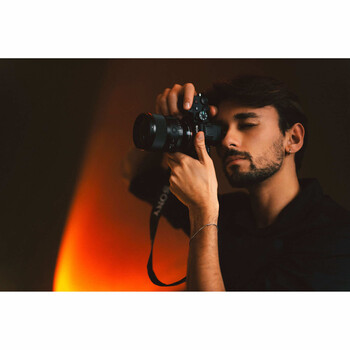 Male photographer holding a DSLR camera to his face while looking through the viewfinder.