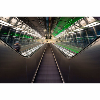 Symmetrical perspective view down a modern subway tunnel with converging tracks and platforms.