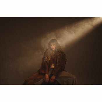 Person seated in dramatic volumetric lighting with warm amber tones and dust particles.