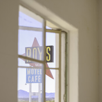 Vintage neon sign visible through a window pane, showing partial text and a star graphic.