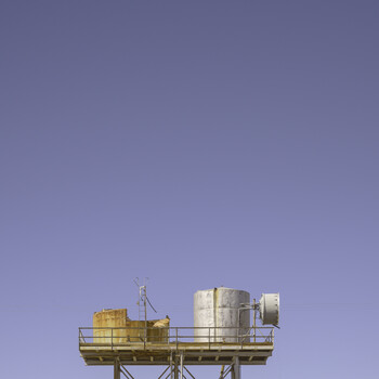 Industrial rooftop structure with yellow and silver cylindrical tanks against a clear blue sky.
