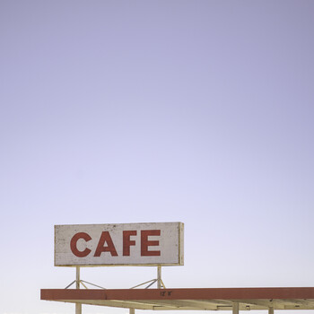 Vintage red and cream café sign mounted on a horizontal beam against a clear sky.