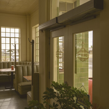 Interior doorway with glass doors opening onto a garden, warm natural light streaming through large windows.