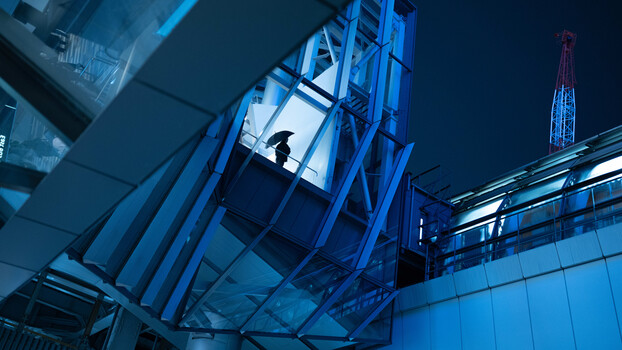 Industrial crane silhouette against night sky with blue-toned architectural steel framework.