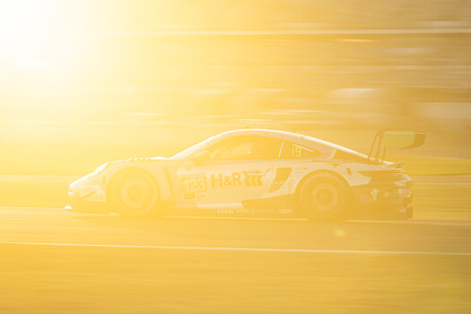 Race car captured in profile against a golden-hour sunset with motion blur effect.