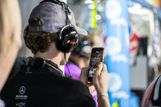 A fan films a pit stop on his phone