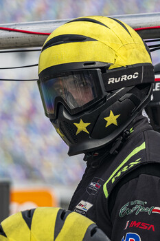 Skier wearing a bright yellow helmet with black stripes and a black face mask decorated with gold stars.