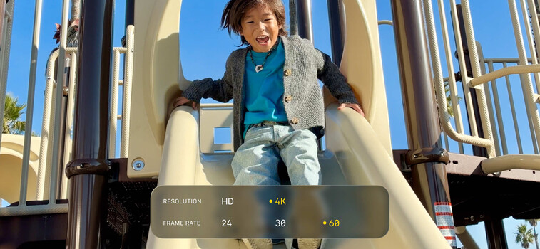 Child sliding down a playground tube with video resolution and frame rate settings overlaid on screen.