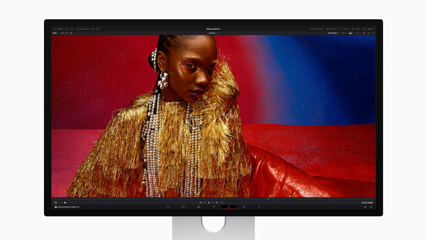 Screenshot of a desktop monitor displaying a portrait of a person wearing a gold sequined jacket against a red and blue gradient background.