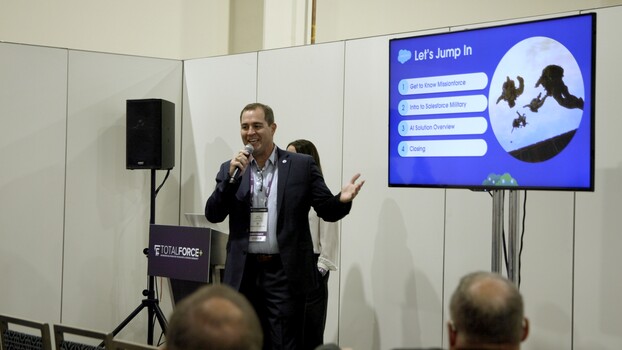Speaker at a conference presenting to an audience with a presentation screen displaying activity options.