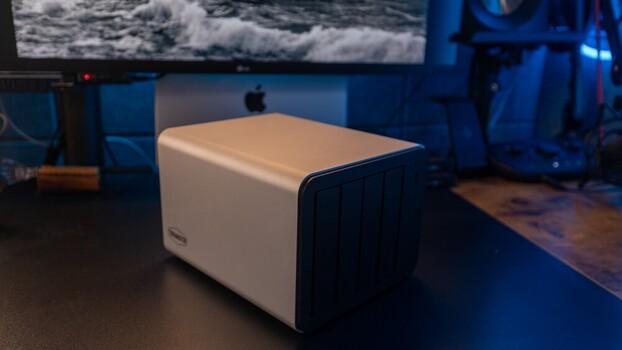 White and black external hard drive on a desk in a blue-lit studio environment.