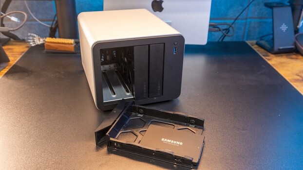 External hard drive dock with Samsung drive partially inserted on wooden desk.