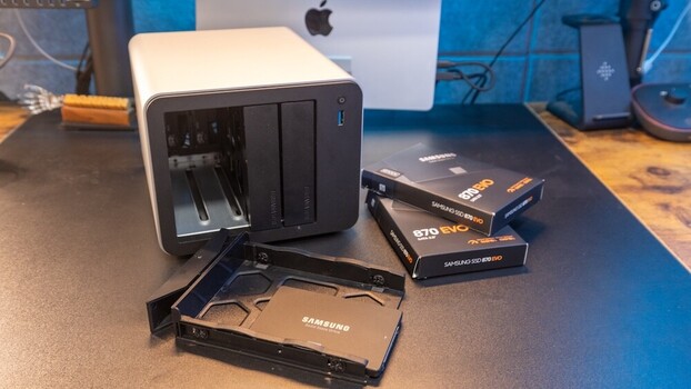 External hard drive with Samsung SSD and accessories displayed on a desk next to a Mac computer.