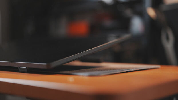 Laptop computer angled on warm-toned wooden desk with blurred background.