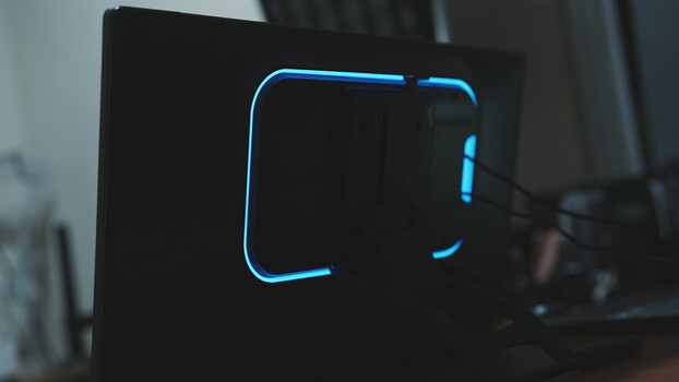 Blue neon lines forming a bracket or frame shape on a black computer case in low light.