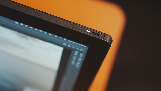 Close-up of a laptop edge with warm orange ambient lighting in the background.