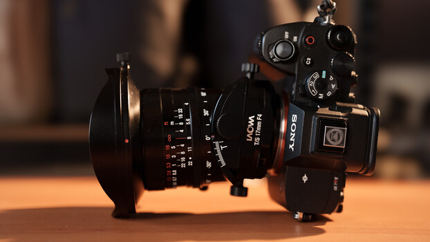 Sony camera with vintage manual focus lens and matte box mounted on wooden surface.