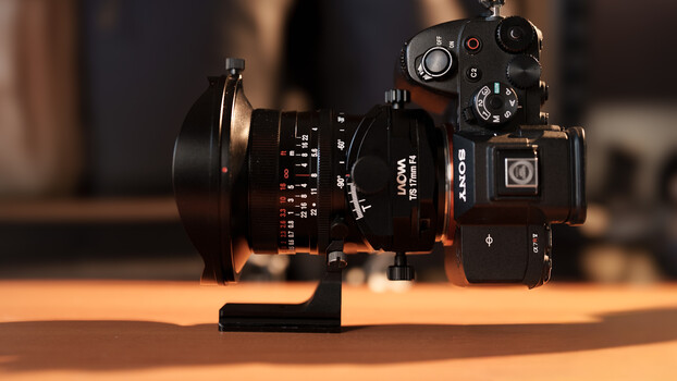 Cinema camera with anamorphic lens mounted on wooden surface with warm backlighting.