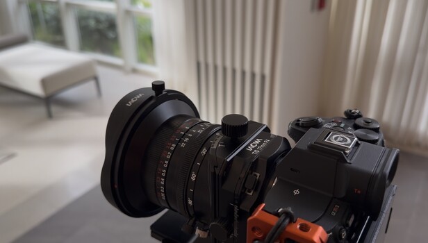 Cinema lens with focus gear and orange follow focus wheel mounted on camera body.
